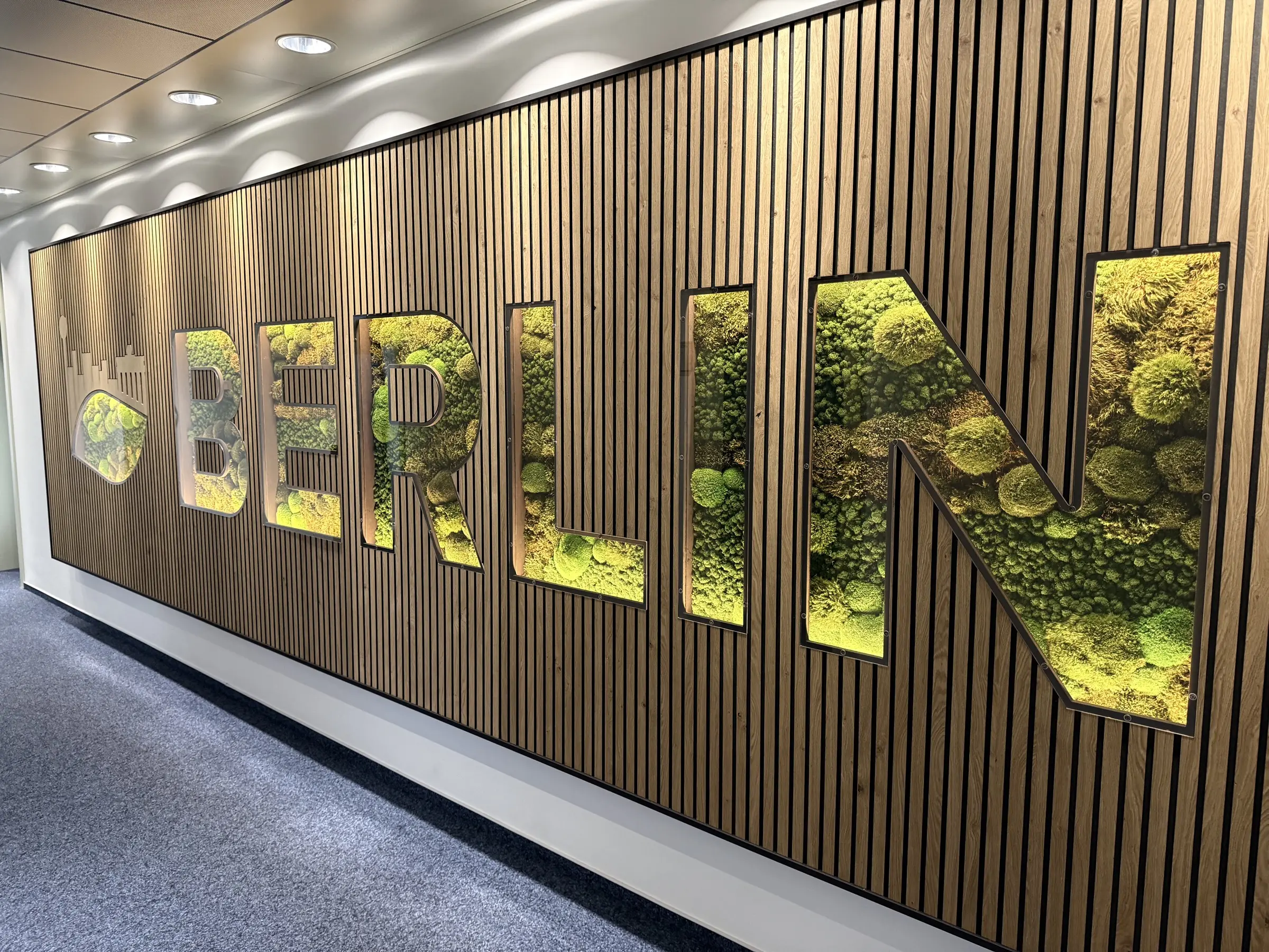 Lamellenwand mit 3D-Schriftzug, gefüllt mit hochwertiger Moosmischung und indirekter LED-Beleuchtung