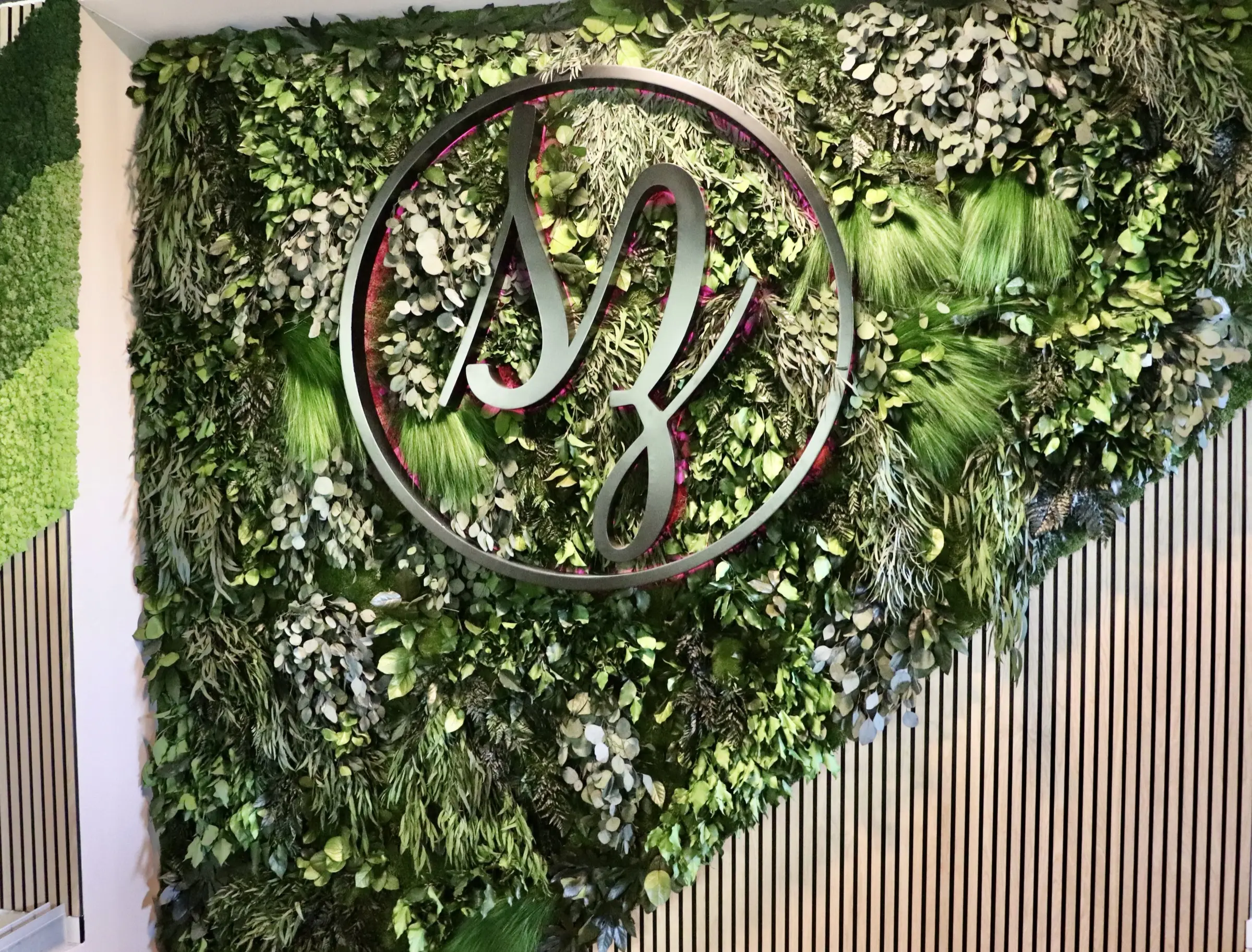 Dschungelinstallation im Showroom für Luxusmöbel. Beleuchtetes Logo in RGB. Abgewinkelter Schnitt in Treppe mit Akustikplatten.