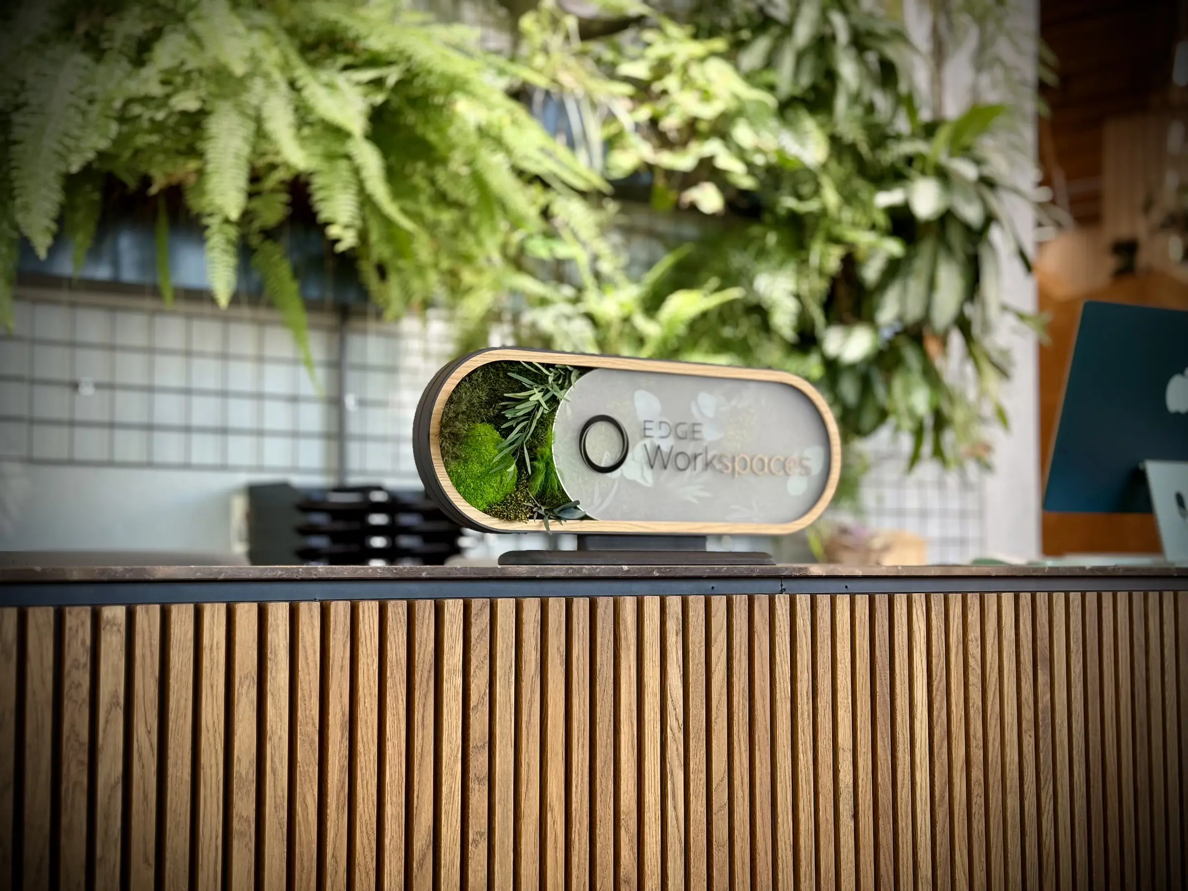 Custom Plexiglass with Edge logo Display with Natural Wood Veneer and Jungle Plant Backdrop