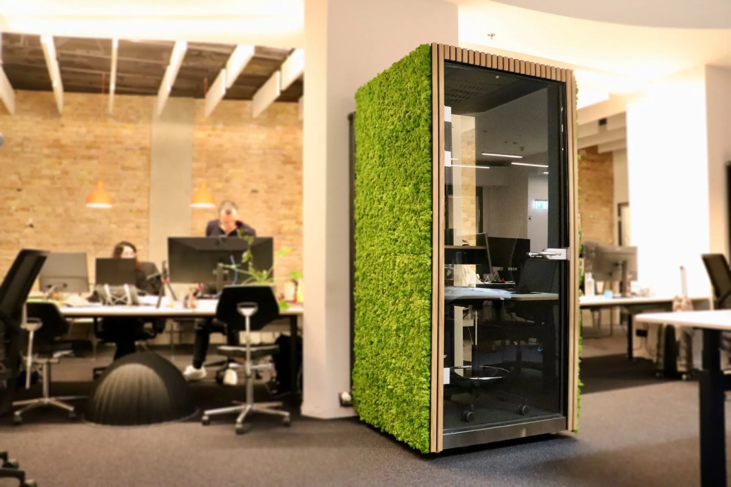 Acoustic phone booth from manufacturer Quiet Office, clad in preserved island moss with front acoustic panels in real oak veneer