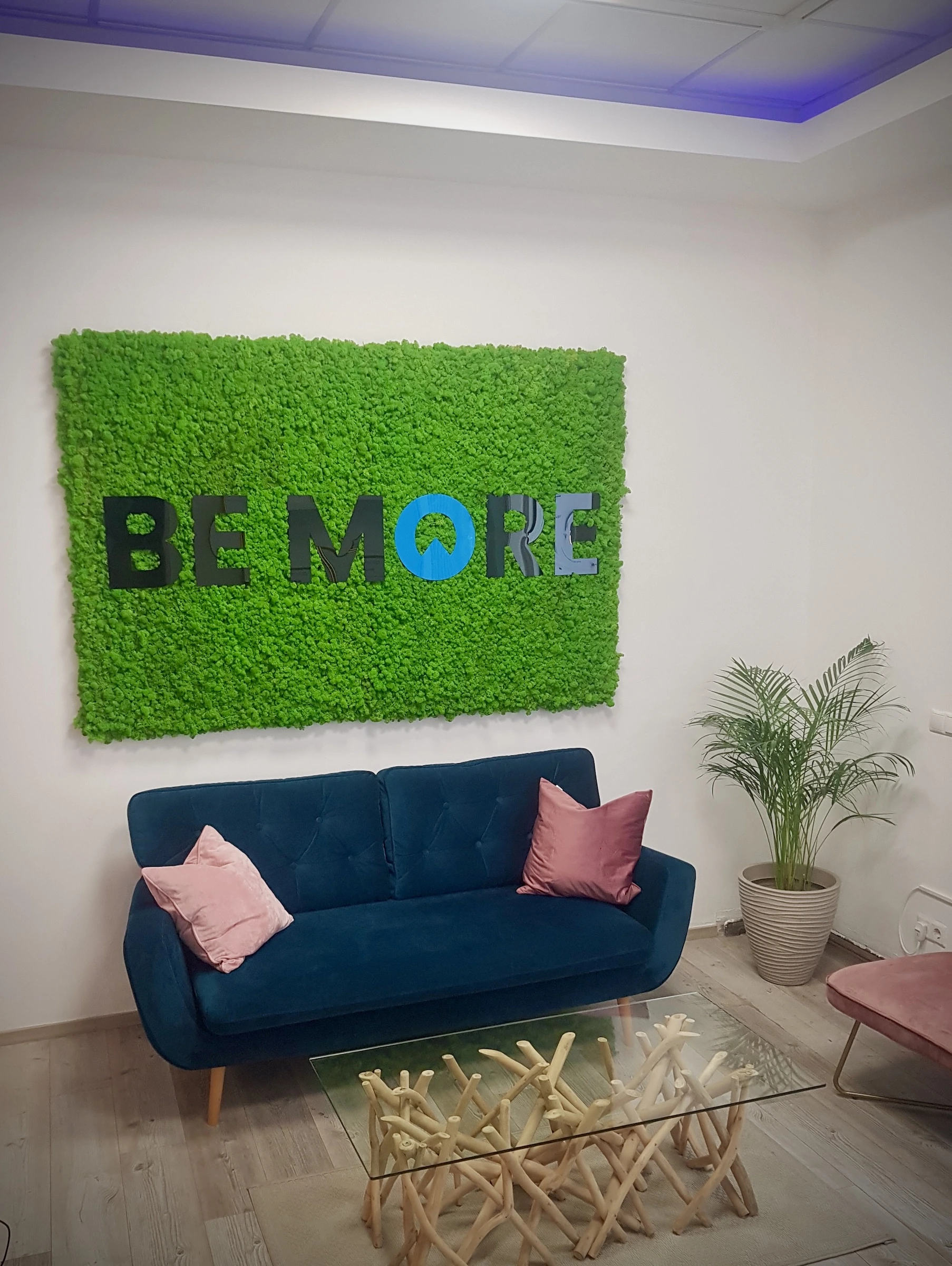 Bespoke island moss panel featuring a “Be More” logo cut from Plexiglas for a modern, illuminated accent