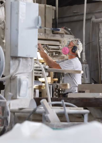 Man in the respirator is making custom stone cutting.
