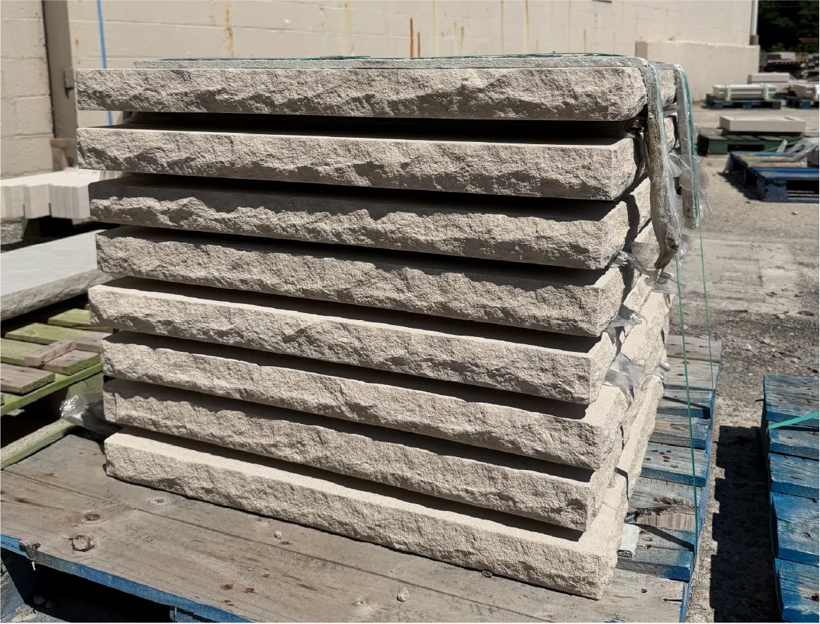 Rock-face limestone pool coping stacked on a pallet