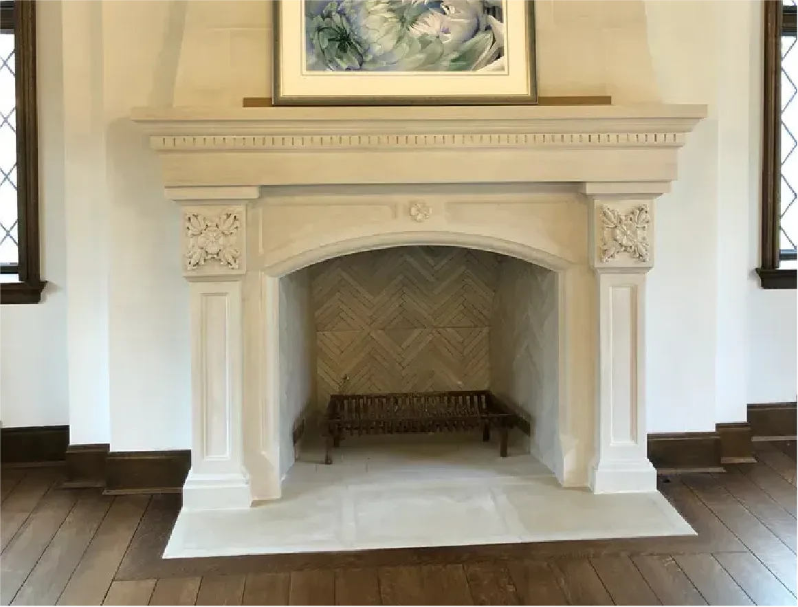 Custom carved limestone fireplace surround with arched opening and rosette details
