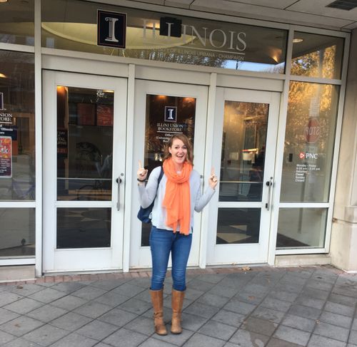 A student at the University of Illinois bookstore, pointing at the sign on the door