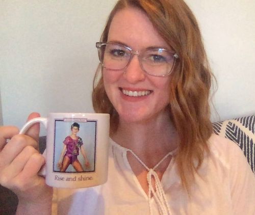 Image of Kara holding a coffee mug that says Rise and Shine.