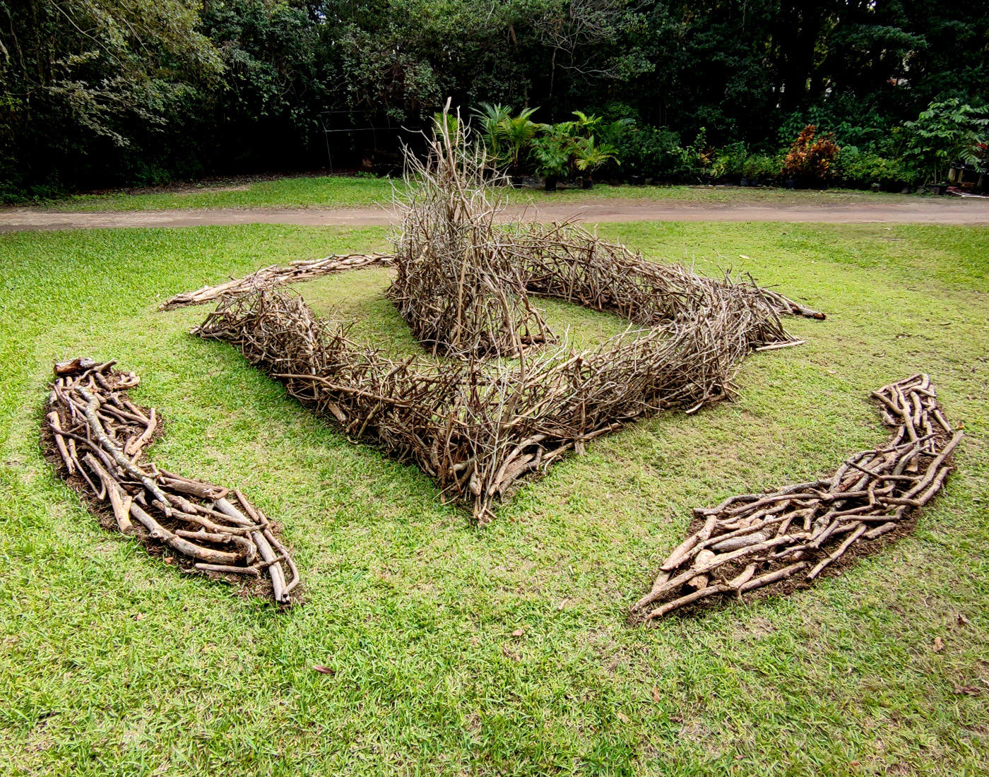 A site-specific installation on Deering Estate for Deering Contemporary 2026, Here We Gather: What we need, we already have, curated by Dainy Tapia. Reflecting on migration as an innate behavior of the human species, this installation opens space for people to process lived experiences and explore the connection between the body, the spirit, and the earth. The installation’s circular form echoes architectural footprints left by the early Tequesta people of South Florida (as seen in the Miami Circle in Downtown, and in the ancient burial site on Deering Estate, where graves are situated in a radial configuration). Anchored on all sides by “gates” which are oriented to the Four Directions (East, South, West, and North), the spiral invites contemplation, urging acknowledgement of the sacred.
