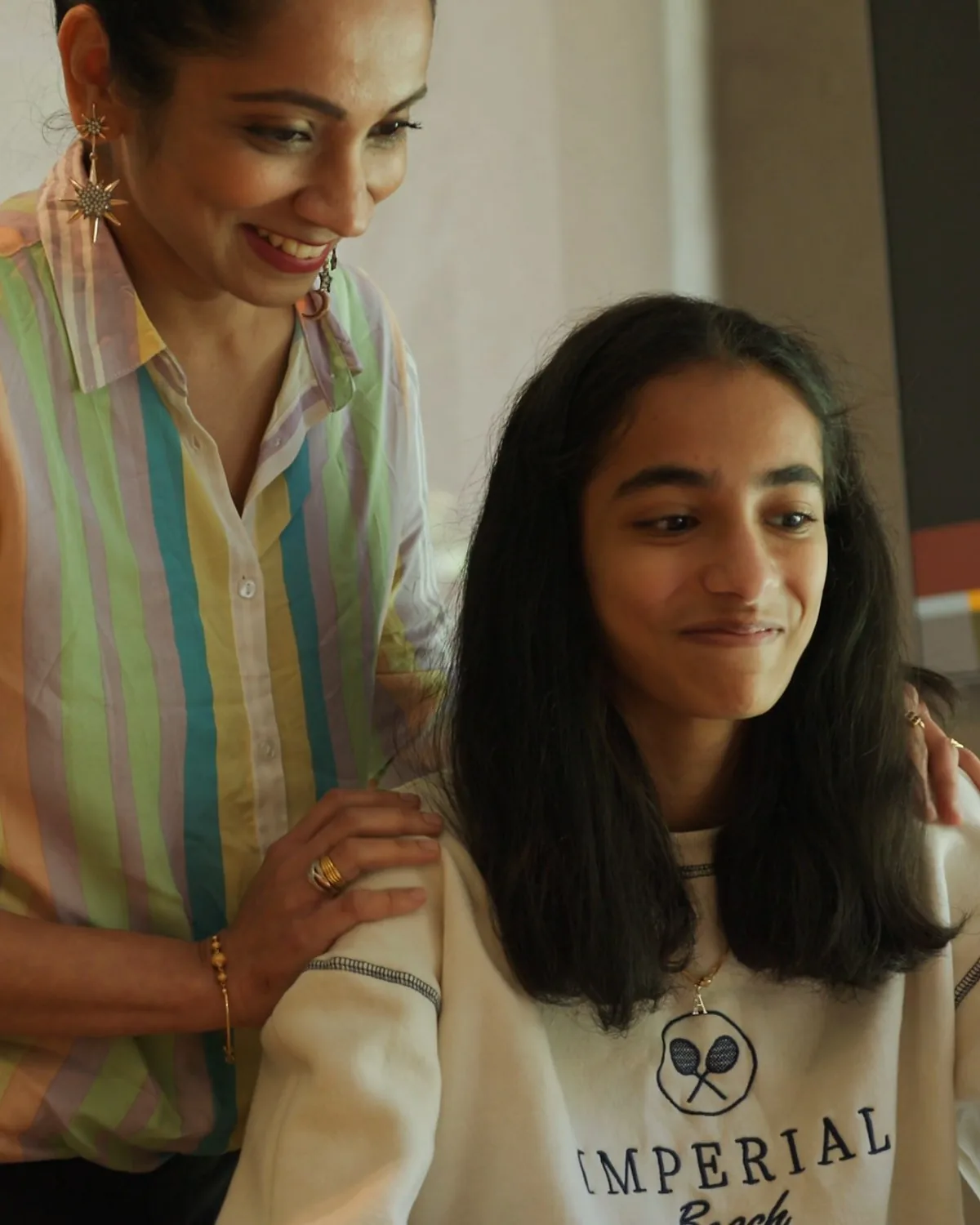 Amrita's mum leaning over her shoulder, both smiling at her maths work
