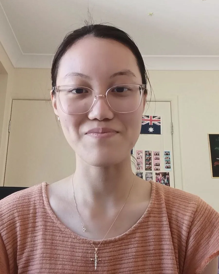 Elena in glasses and an orange top, smiling at the camera during her interview