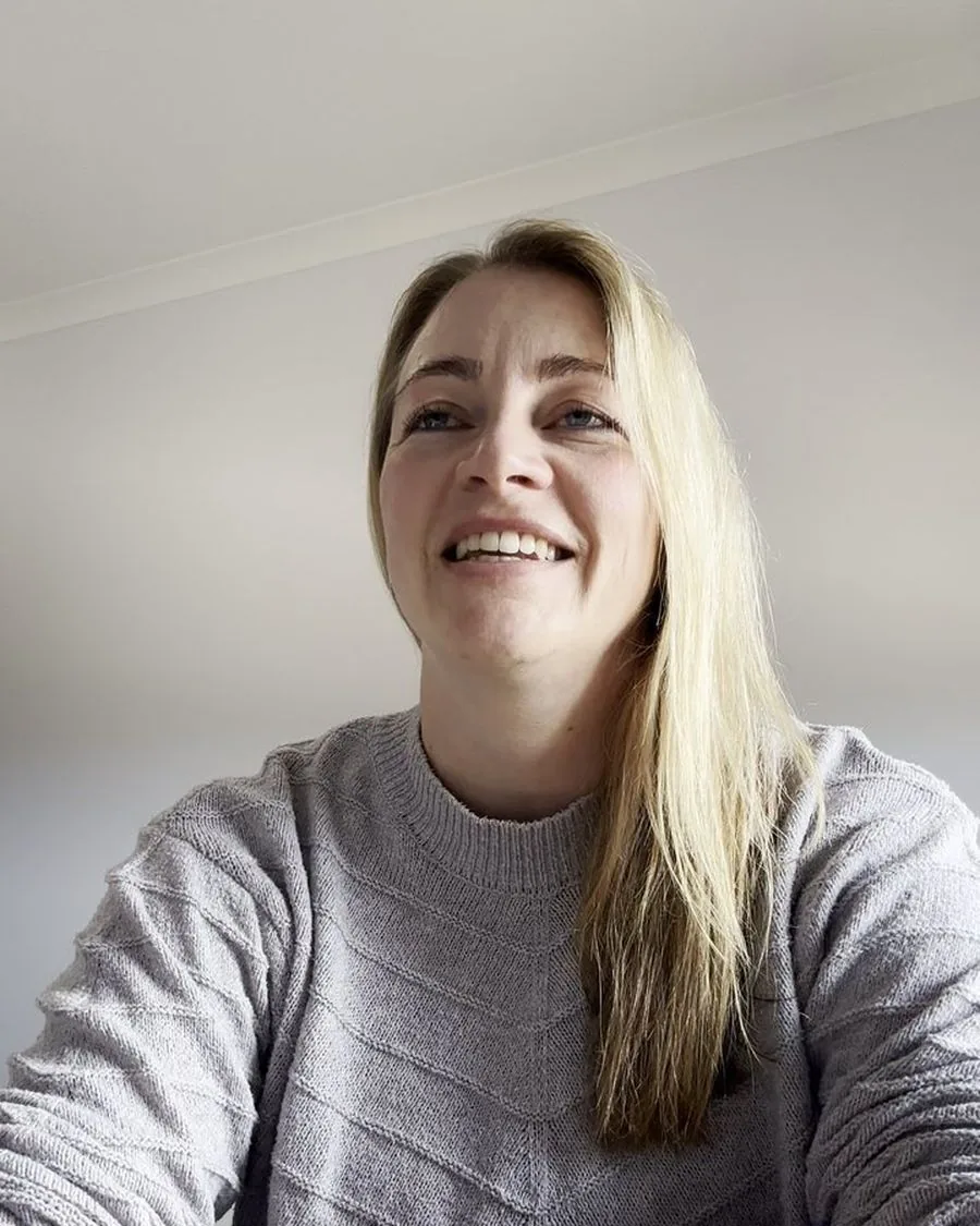Jayne, smiling, leaning on her arms at a table during her interview about Mia's chemistry tutoring