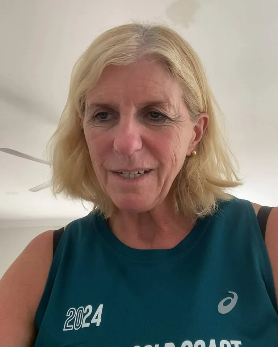 Jules, Clara's mum, in a Gold Coast 2024 running singlet, talking on a video call at home