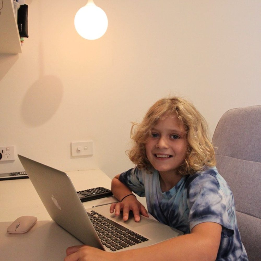 Young student smiling at his desk during an online lesson