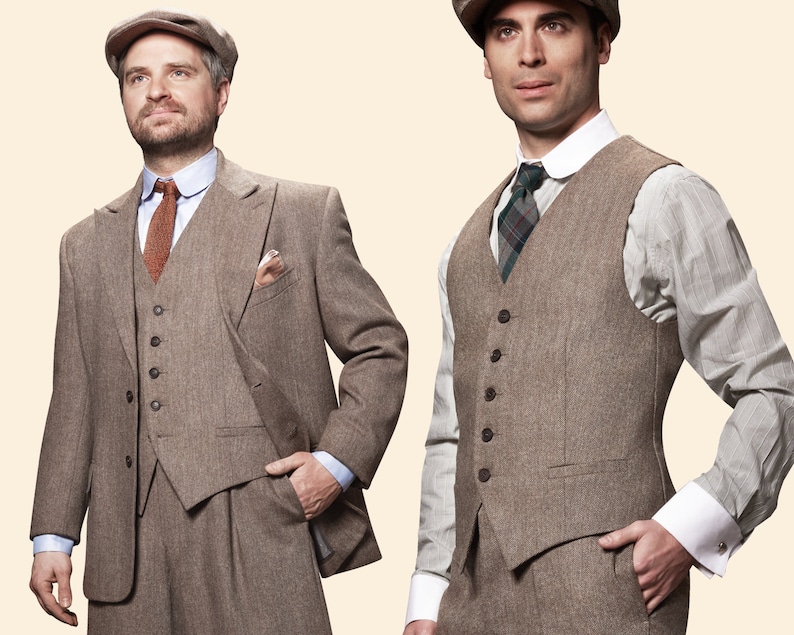 May include: Two men wearing brown tweed suits with vests. The man on the left is wearing a brown cap and a brown and orange tie. The man on the right is wearing a brown cap and a plaid tie.