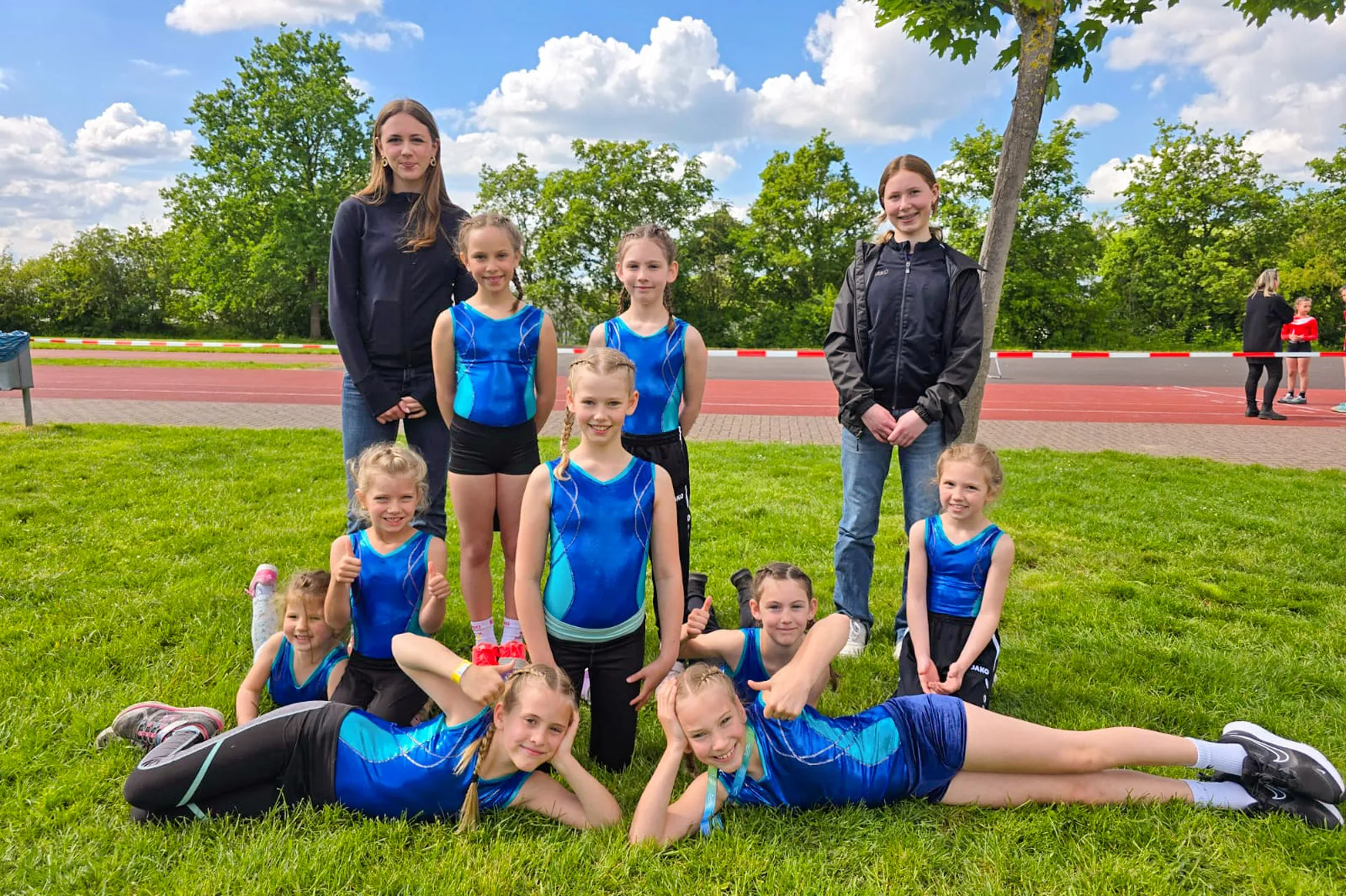 Turnerinnen des TSV Krofdorf-Gleiberg mit ihren Trainerinnen auf der Wiese des Sportplatzes.