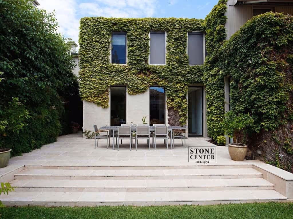 flagstone patio in front of a house covered in vines