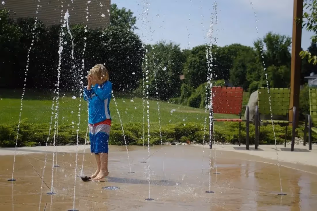 kid playing around splash pad in the backyard
