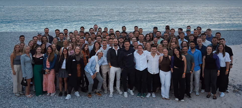 simpleclub Mitarbeitern bei einem Teamevent am Strand bei Sonnenuntergang. Unterstützt die Botschaft "Wir suchen die besten Talente
