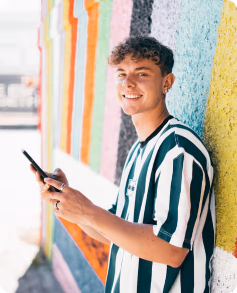 Junger Mann lächelt, während er die simpleclub App auf seinem Smartphone für mobiles Lernen nutzt.