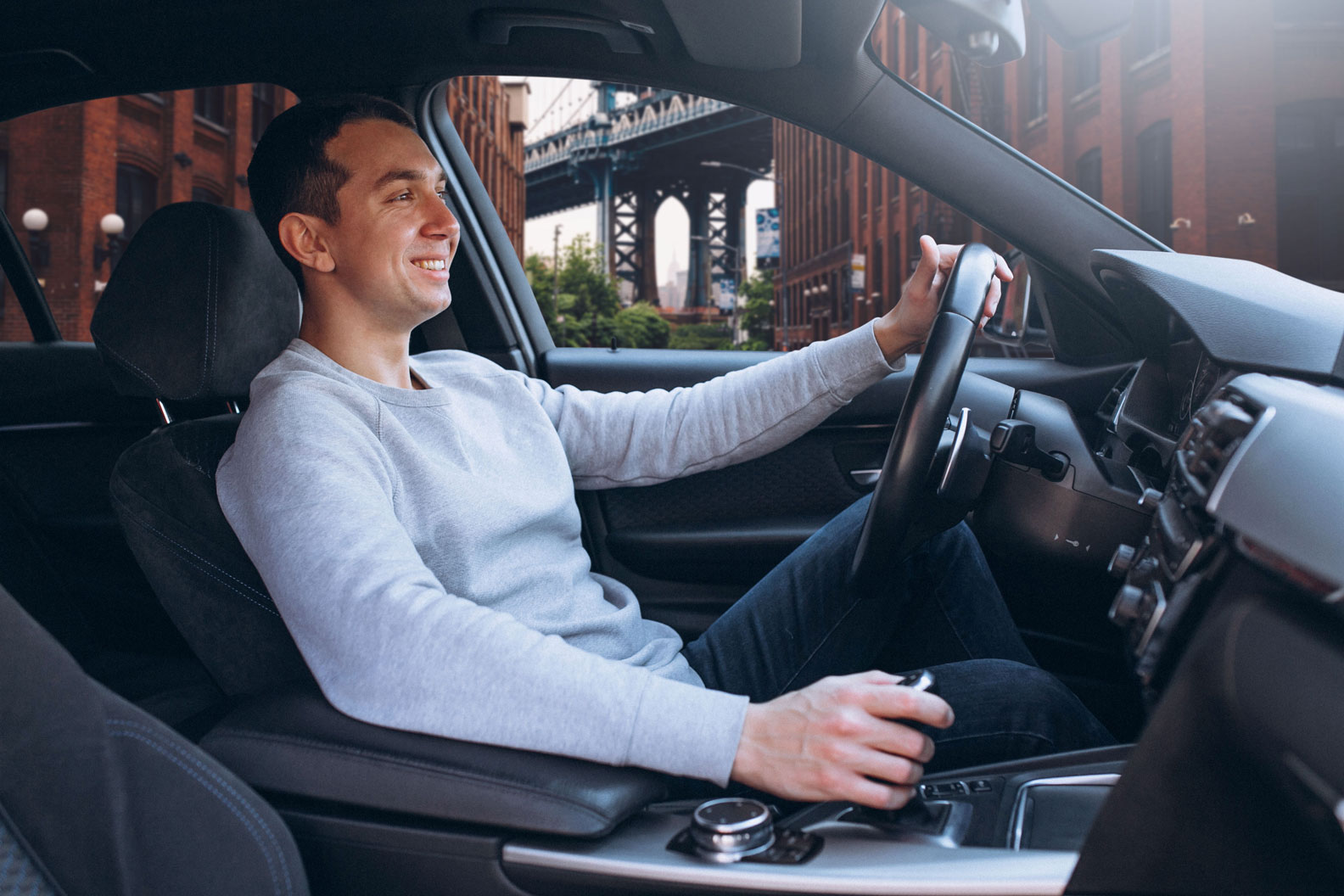 Image of a driver inside a car and the New York city at the background