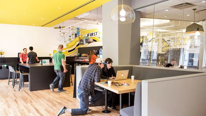 A man kneeling down in front of a woman with a laptop.