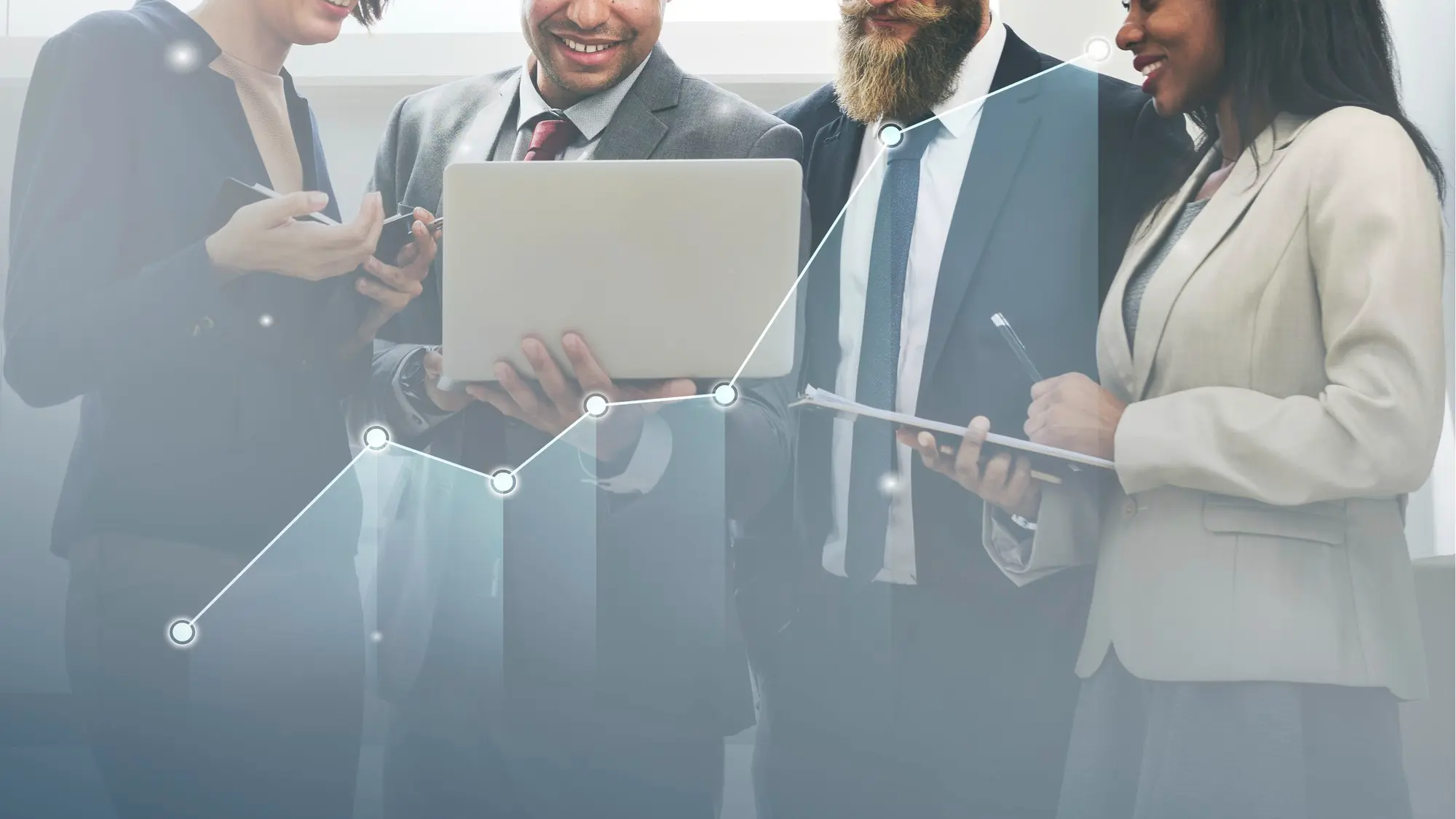 Smiling businesswoman in black suit talking on office desk phone while holding a pen.