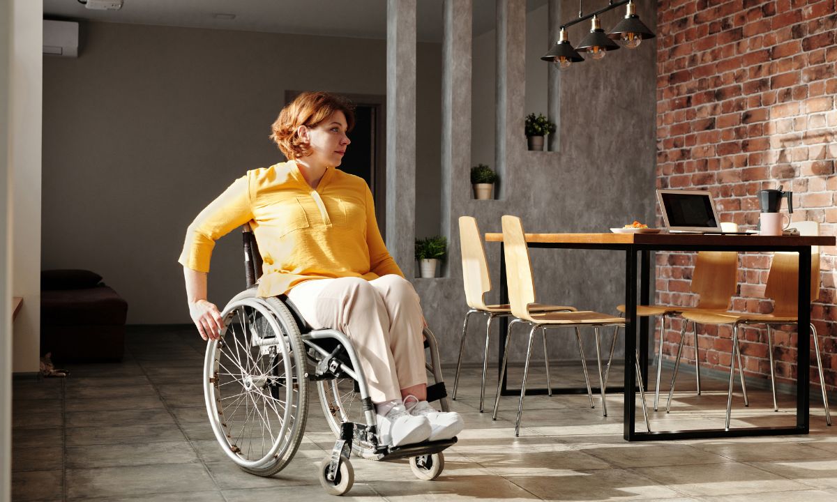 Woman in a wheelchair at a home dining table, illustrating accessing NDIS support after serious injury