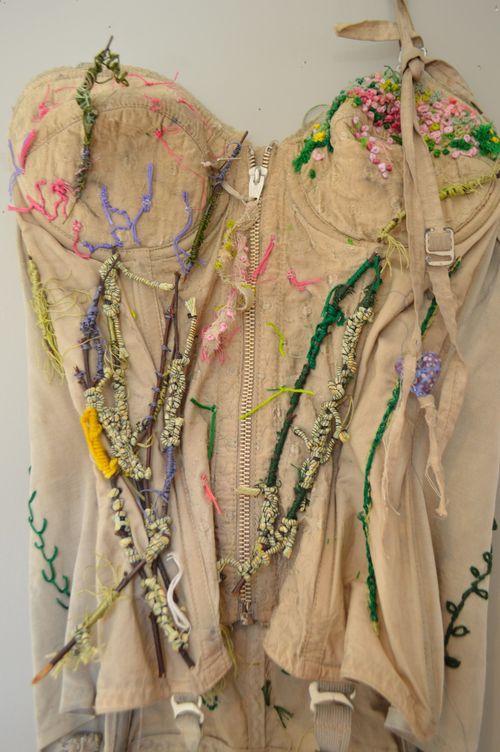 "hint of spring" (detail) 2024, 53" x 11", vintage bustier, natural dyes, botanical dyed silk ribbons, embroidery threads, and twigs