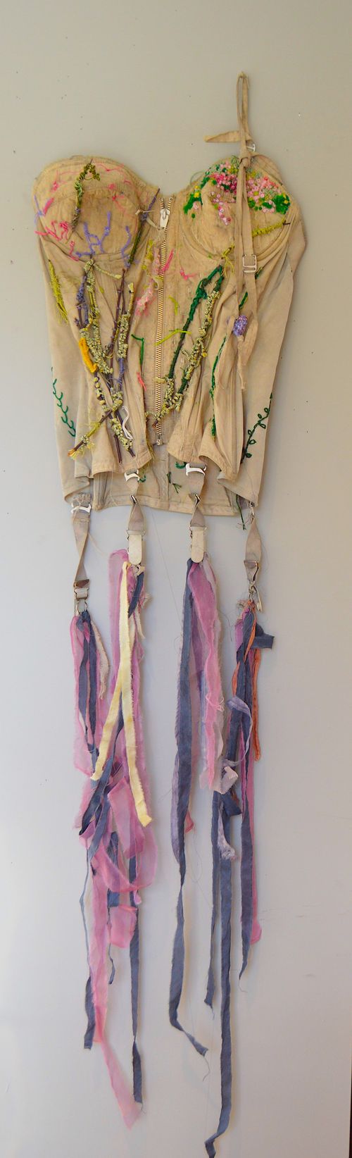 "hint of spring" 2024, 53" x 11", vintage bustier, natural dyes, botanical dyed silk ribbons, embroidery threads, and twigs