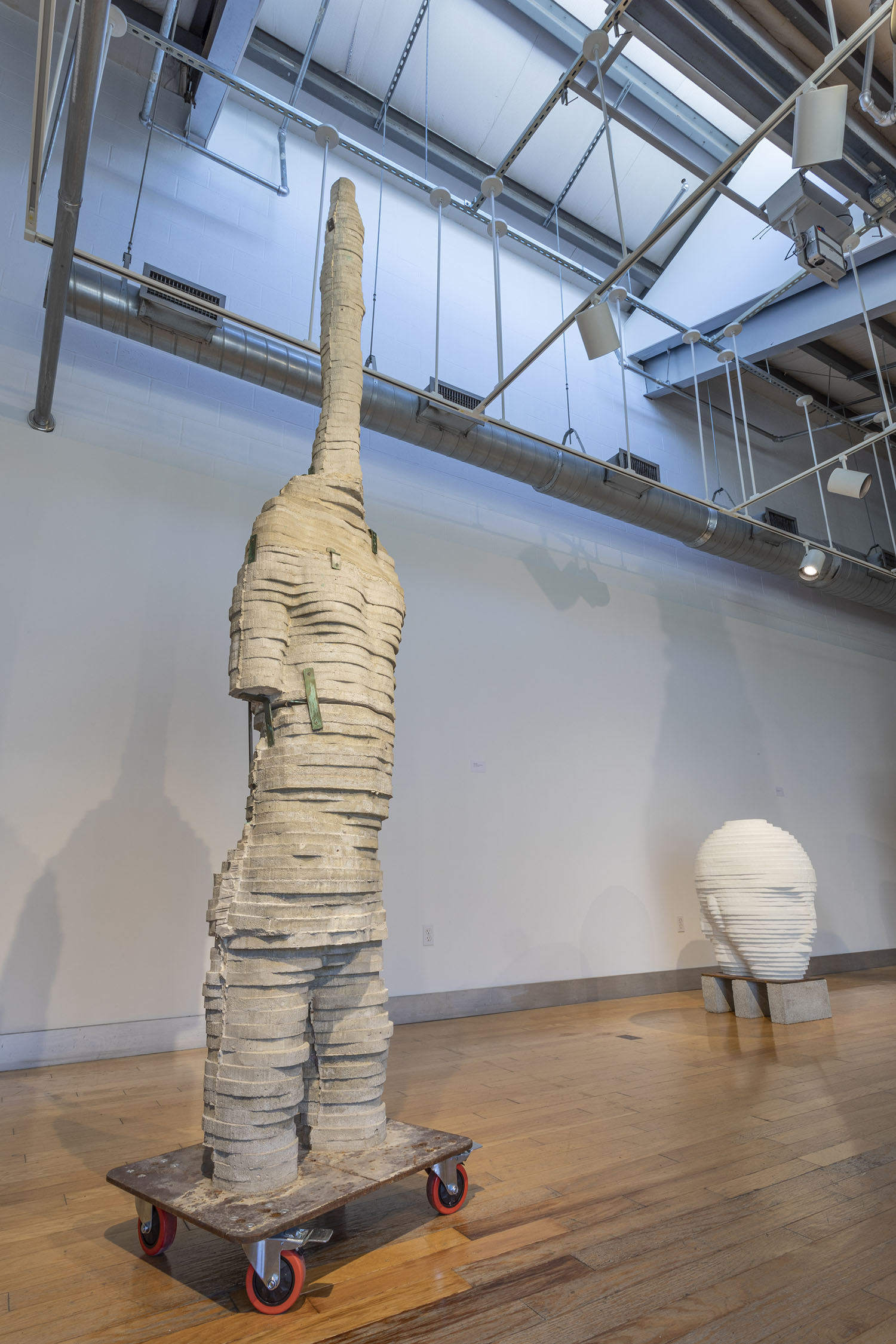 “Long Neck” (left) 2020, concrete, This work is made from a digitally elongated and distorted scan of my body.10’ x 28” x 16” “White Head” (right) concrete, 44” x 22” x 30”