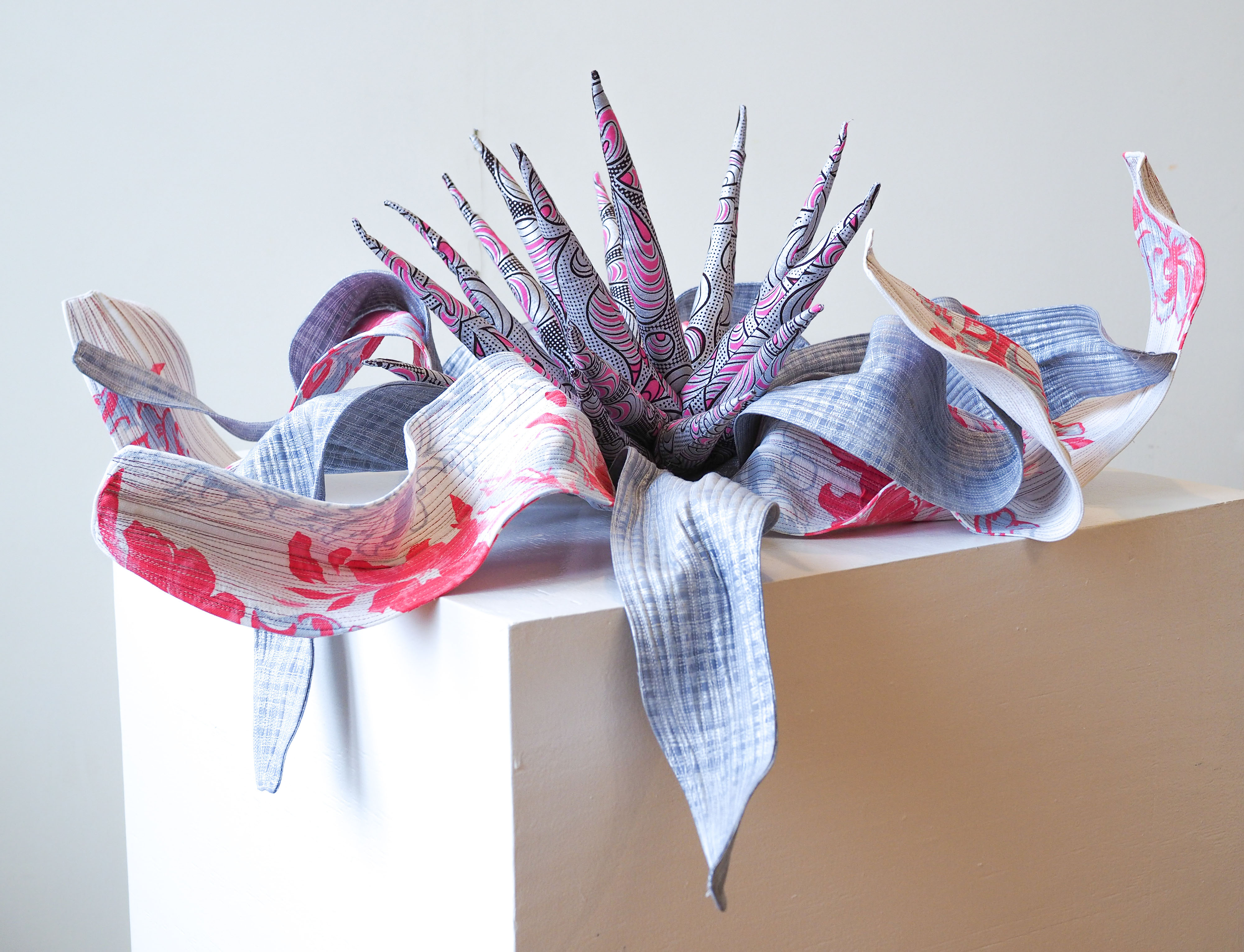 “Echinacea purpurea XI: Silver on my Mother-in-law’s tablecloth” 2023, Machine quilted, hand and machine constructed. Tablecloth & silver Dutch wax fabric, cotton & other textiles, wire, polyester stuffing, cotton batting, thread. 12” h x 30” w x 30” d