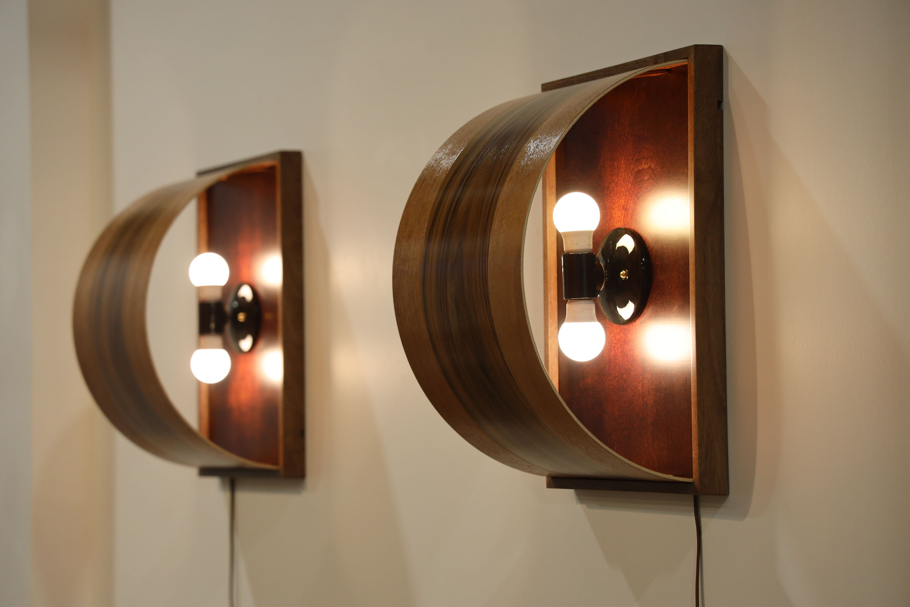 "Halfpipe Sconce" 2023, rosewood + mahogany drum shell fragments. Mahogany frame, ceramic fixture, LED bulbs, 20” x 14”