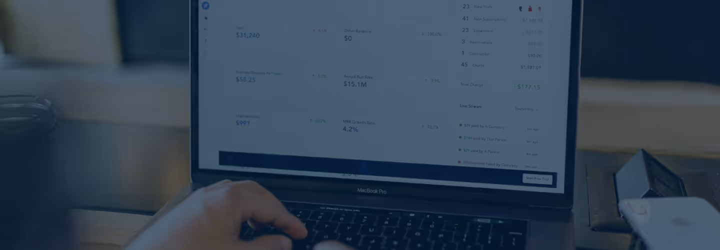 A person using a MacBook Pro reviewing a dashboard interface with charts and metrics, showing figures for total revenue, annual run rate, MRR growth rate, and user activity data.