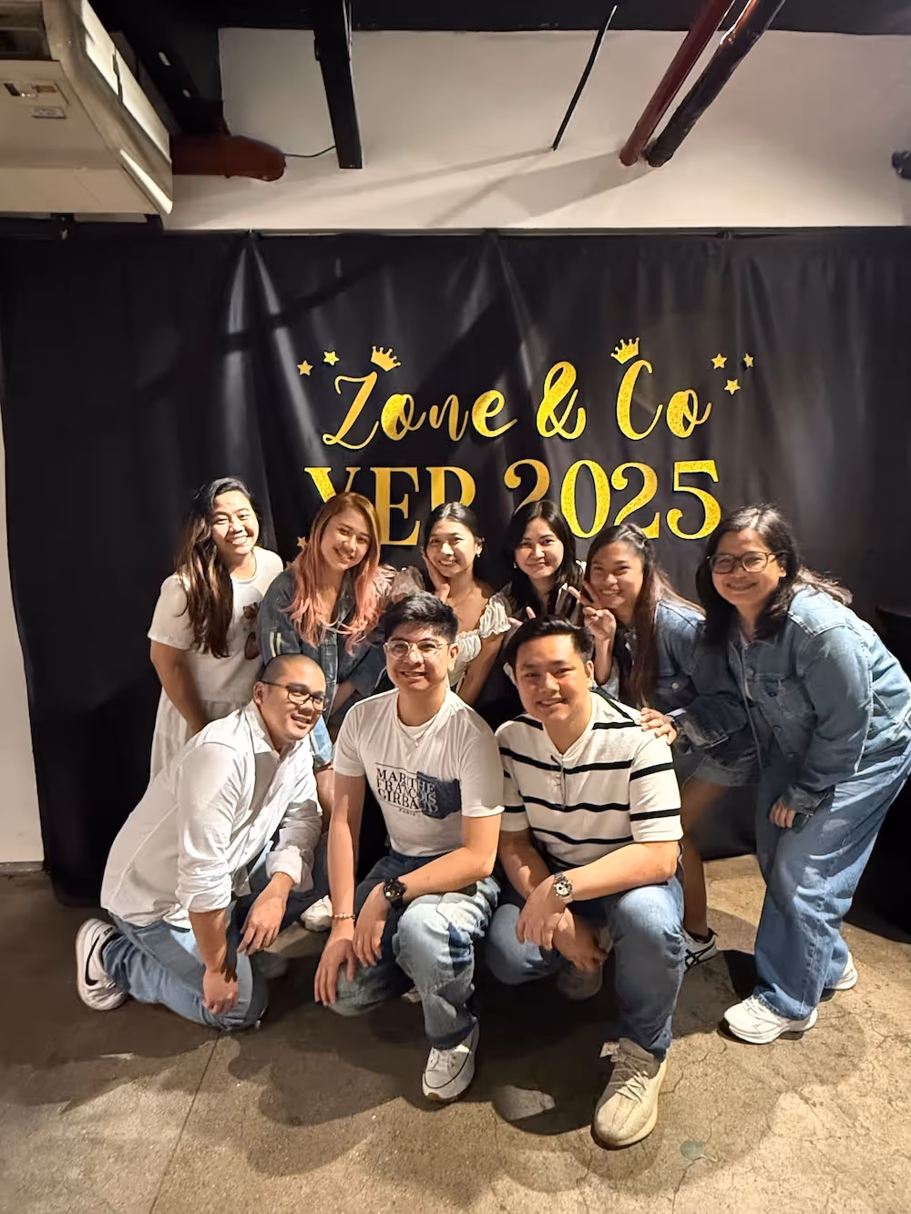 Group of eight people smiling and posing in front of a black backdrop with gold text reading 'Zone & Co YEP 2025'.