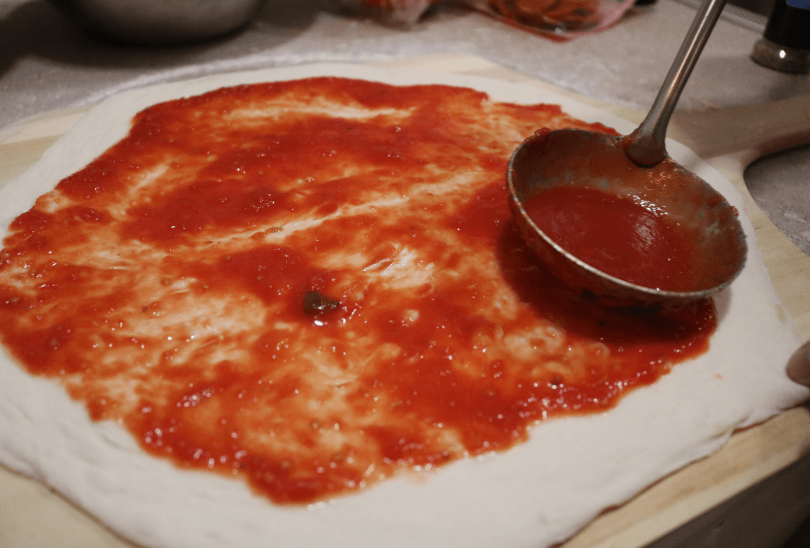 A pizza being sauced