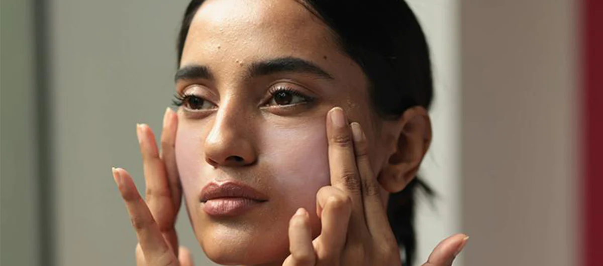 Woman applying sunscreen to her face.