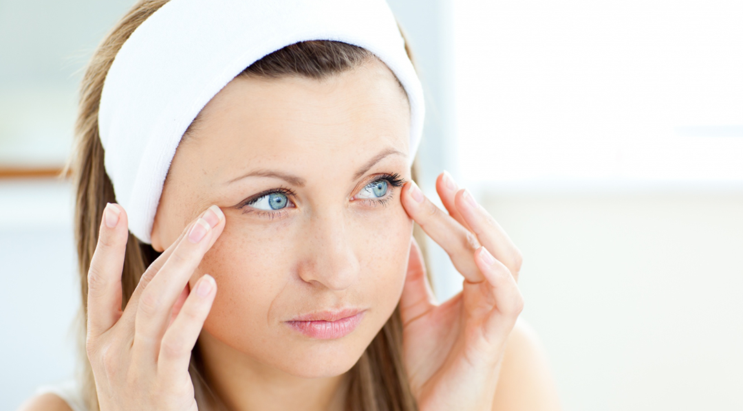 Young woman putting cream on her face wearing a headband in the bathroom