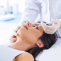A medical professional administering an injection near a woman's eye in a clinical setting.
