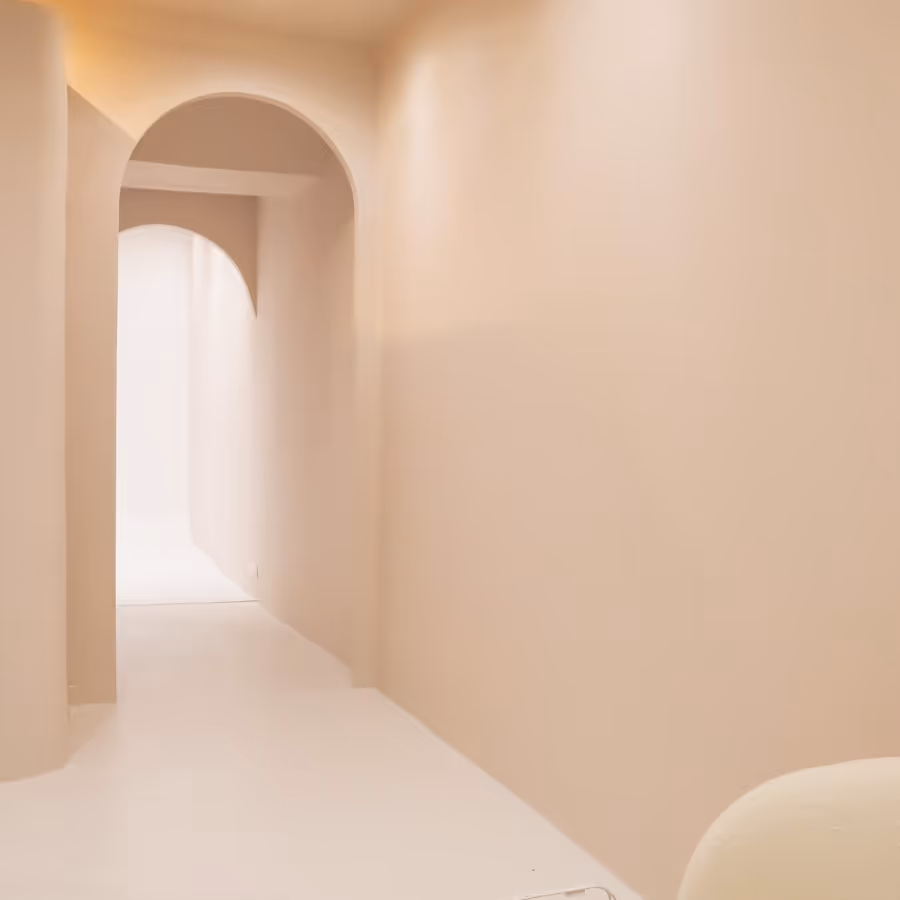 An empty hallway with a white chair and a white wall