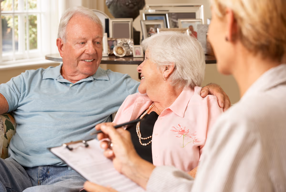 A senior couple looking at each other while senior advisor taking notes