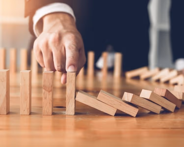 Mans finger holding block from tipping over