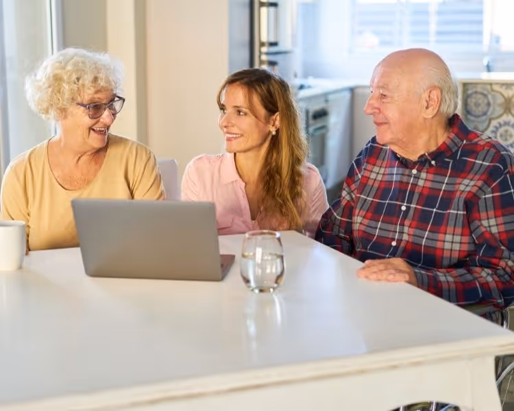 Two seniors and a young lady sitting at a table with a laptop
