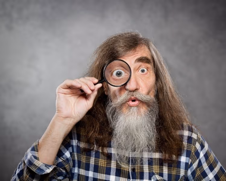 Man looking trough a magnifying glass