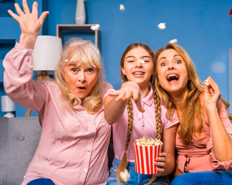 3 generations enjoying a movie eating popcorn