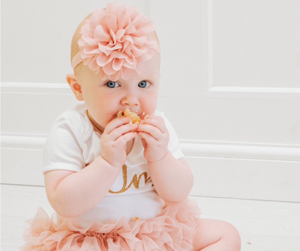 A baby girl munching down on her first birthday cake during her cake smash photoshoot. Gemma Randall Photography ©