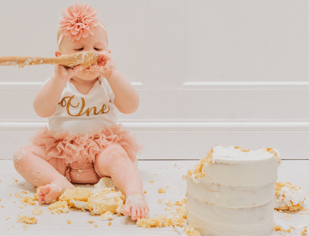 A baby girl cheekily eating her first birthday cake during her cake smash photoshoot. Gemma Randall Photography ©