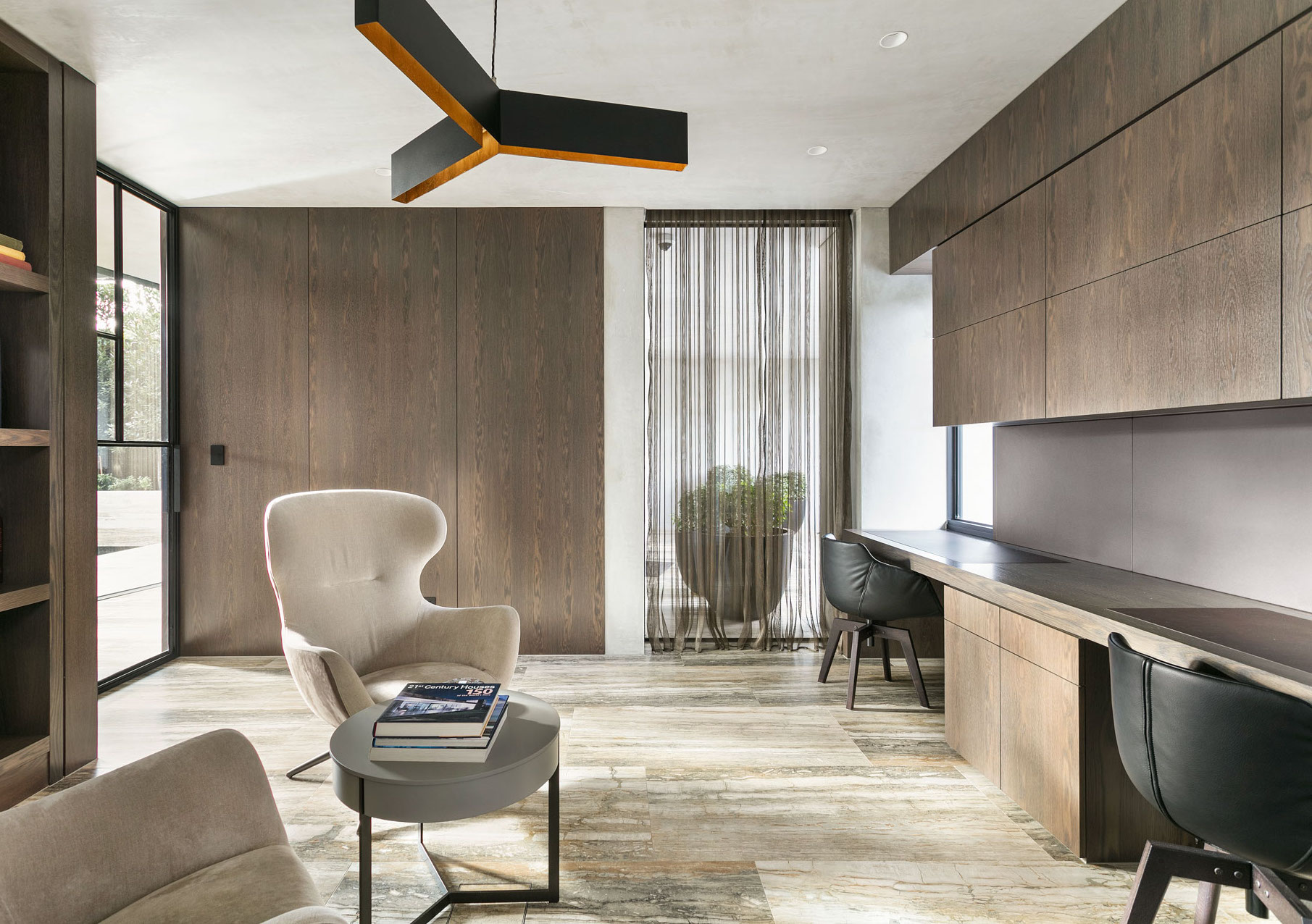 Contemporary home office and reading area in a Melbourne residence by BG Construction, featuring custom timber cabinetry, stone tile flooring, and minimalist furnishings