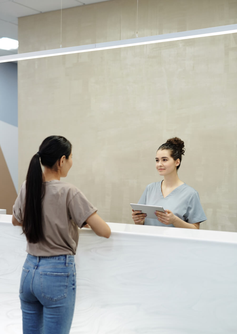 Bilde av en pasient som snakker med resepsjonisten.