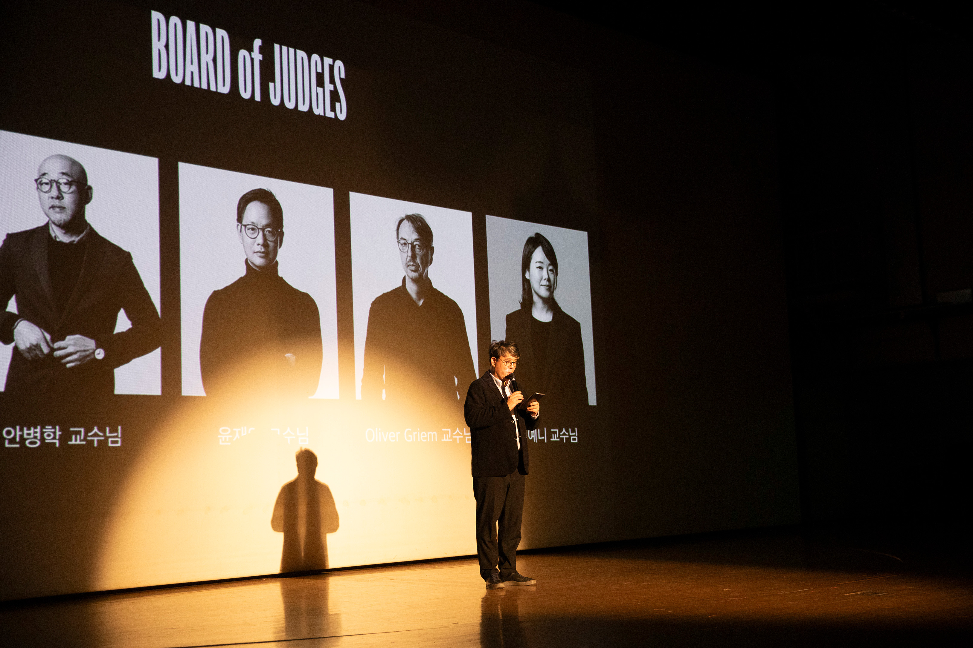 장동련 교수 정년기념 강연 현장 사진. 의자에 앉아 강연을 하고 있는 장동련 교수의 뒷 배경으로는 디자인 노마드라고 적힌 발표자료가 틀어져 있다.