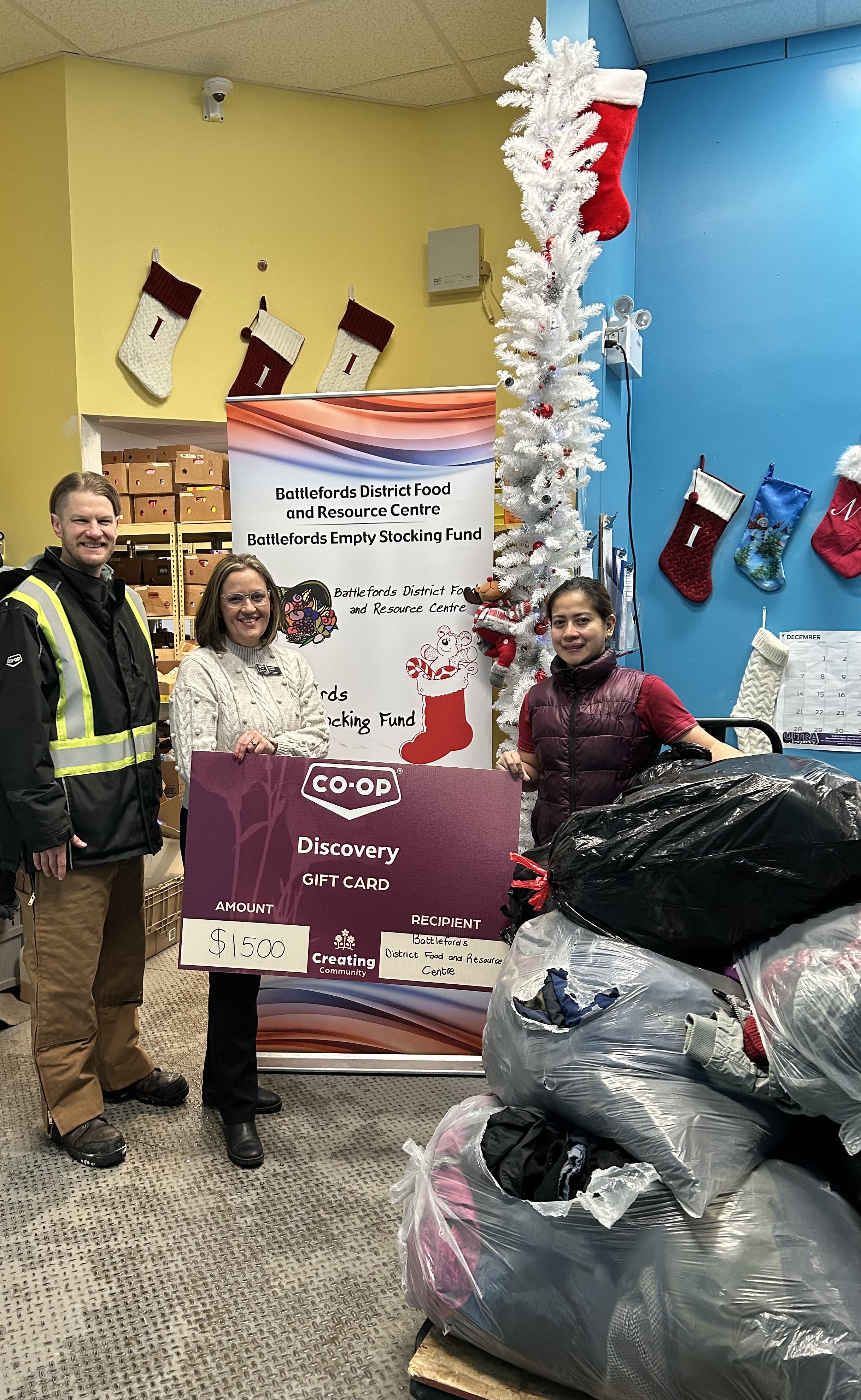 Discovery Co-op staff standing with donated winter jackets and gift cards collected for the ESF.