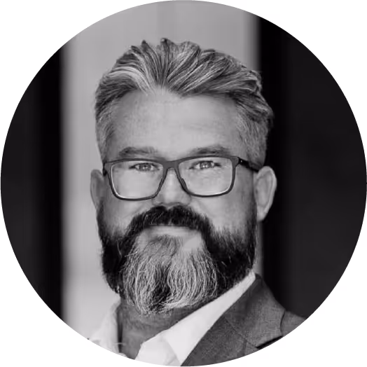 Bearded man with glasses in a suit, monochrome portrait.